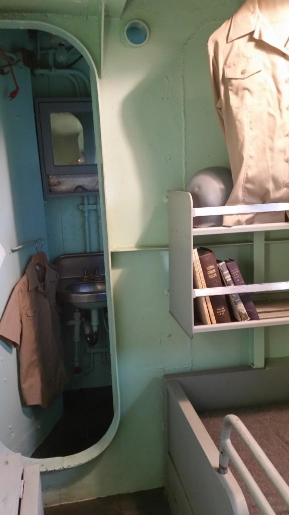 View of the captain's sea cabin showing door to his private head.  Note the helmet on the shelf. 
